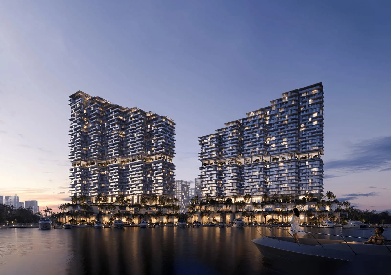 Riviera Residences: twin waterfront towers lit at dusk, reflected in the water.